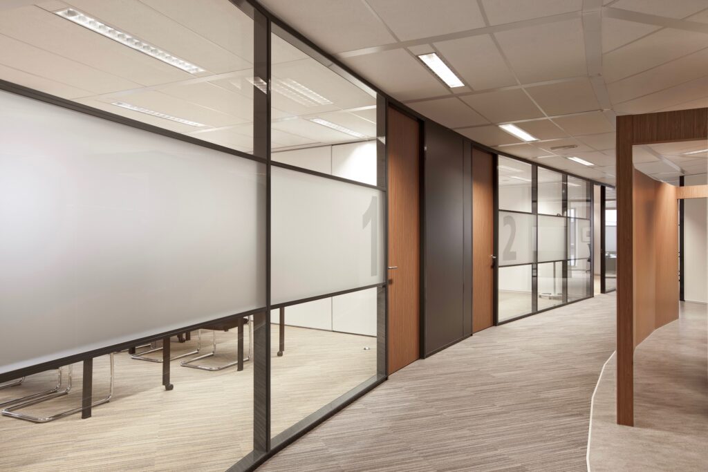 Kantoor gang met glazen vergaderruimtes en moderne inrichting.