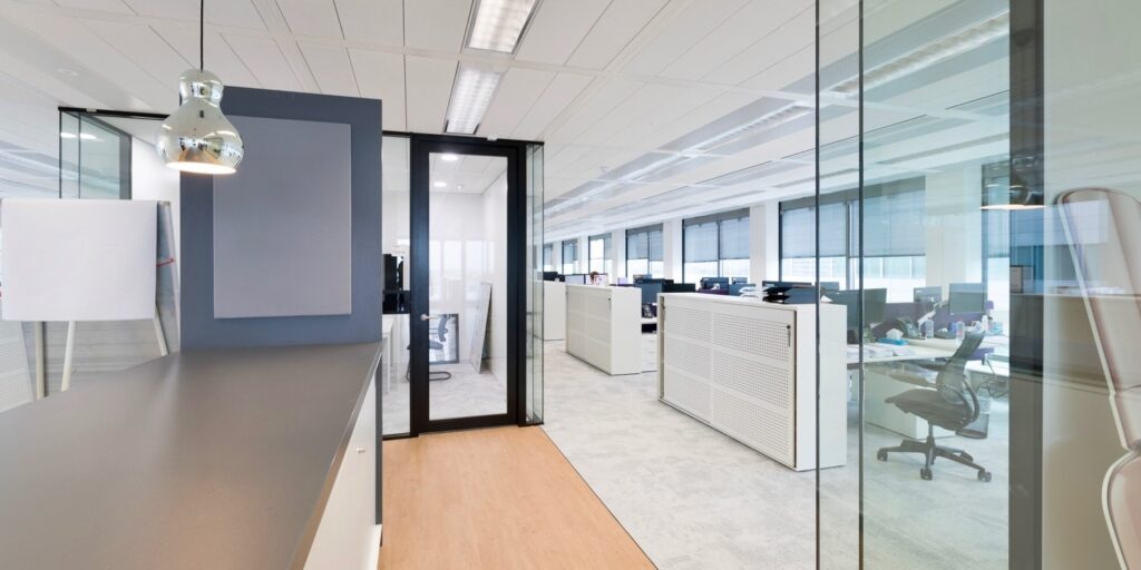 Modern kantoorinterieur met glazen wanden en lichte werkplekken.
