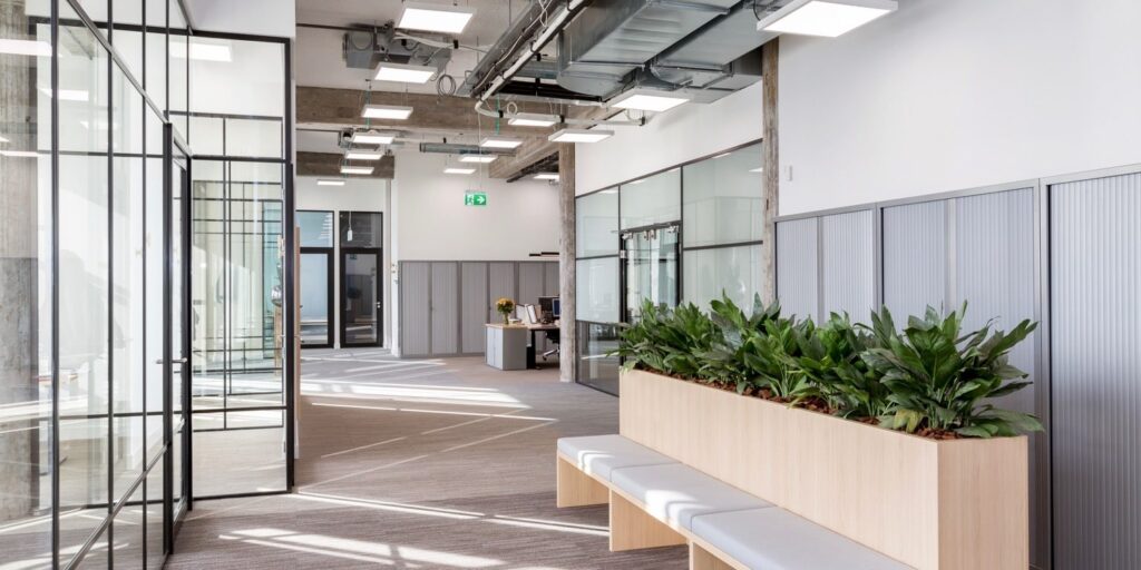 Modern kantoor interieur met glazen wanden en plantenbak.