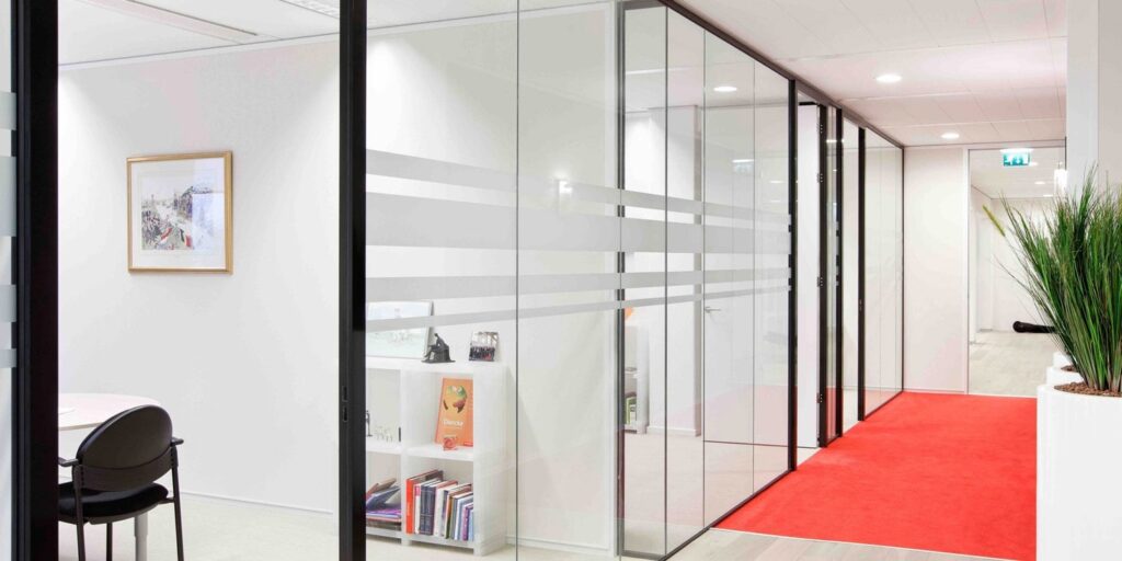 Modern kantoor met glazen wanden en rode loper.