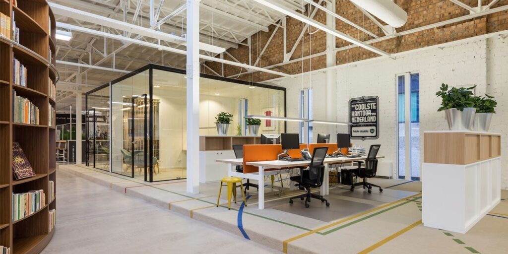 Modern kantoor interieur met bureau's, vergaderruimtes en boekenkast.
