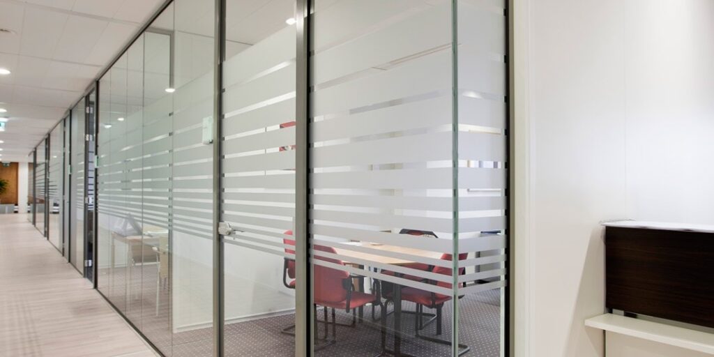 Glazen kantoorruimtes met vergaderruimte, afgeplakt met strepen voor privacy.