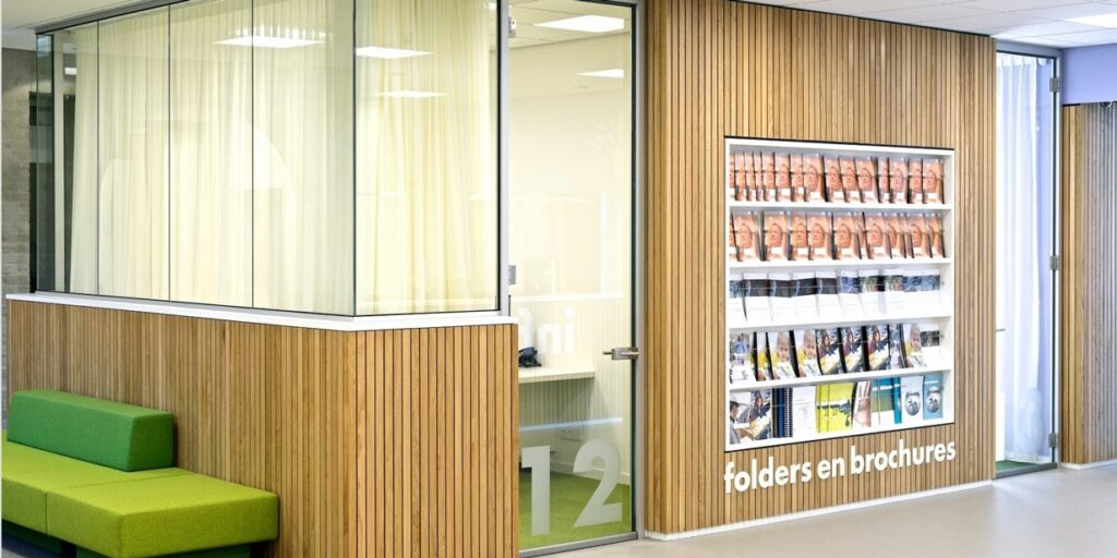 Kantoor wachtruimte met folders en brochures op een wandrek.