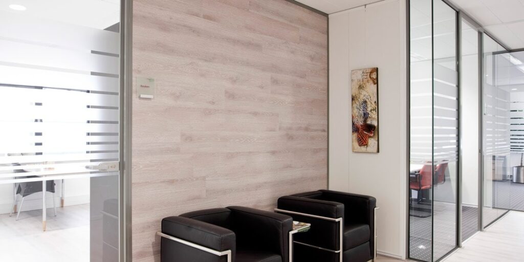 Wachtruimte in kantoor met zwarte zetels en glazen wanden.