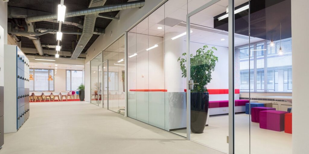 Modern kantoorinterieur met glazen wanden en kleurrijke elementen.