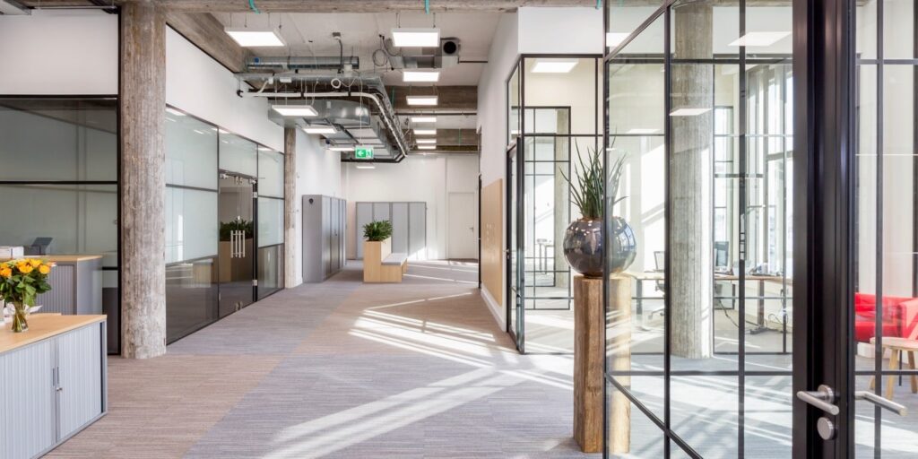 Modern kantoor interieur met glazen wanden en planten.