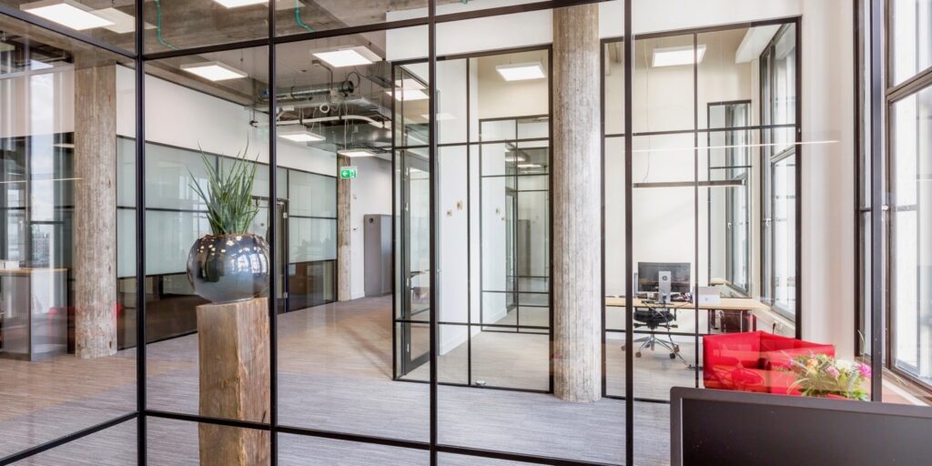 Modern kantoor interieur met glazen wanden en planten.
