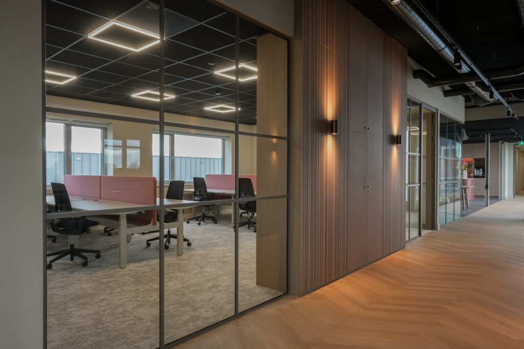 Moderne kantoorruimte met glazen wanden en bureaus.