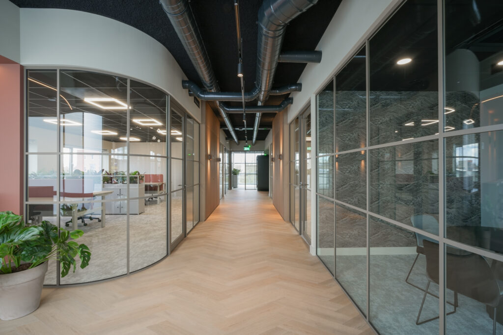 Kantoorgang met glazen wanden en moderne inrichting.