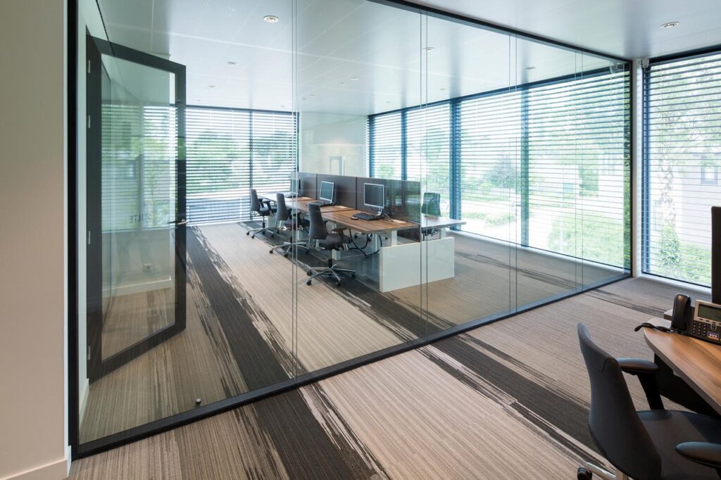 Glazen kantoorruimte met moderne werkplekken en bureau's.