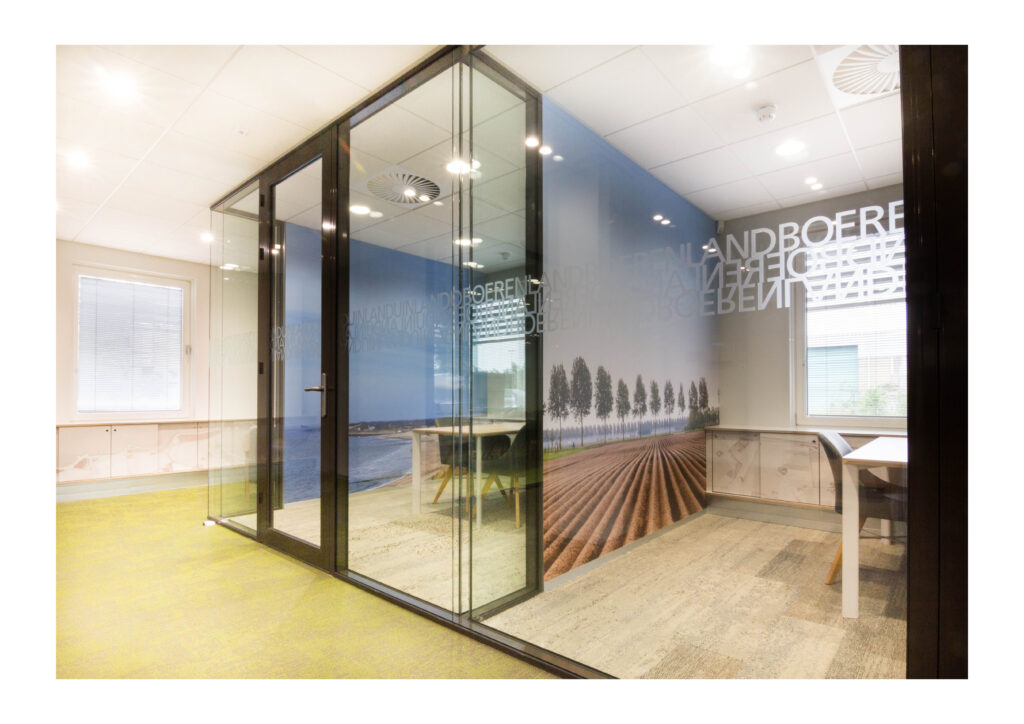 Glazen kantoorruimte met moderne werkplekken, een bureau en muurtekening.