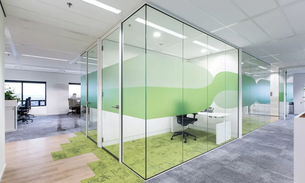 Moderne kantoorruimte met glazen wanden en groene decoratie.
