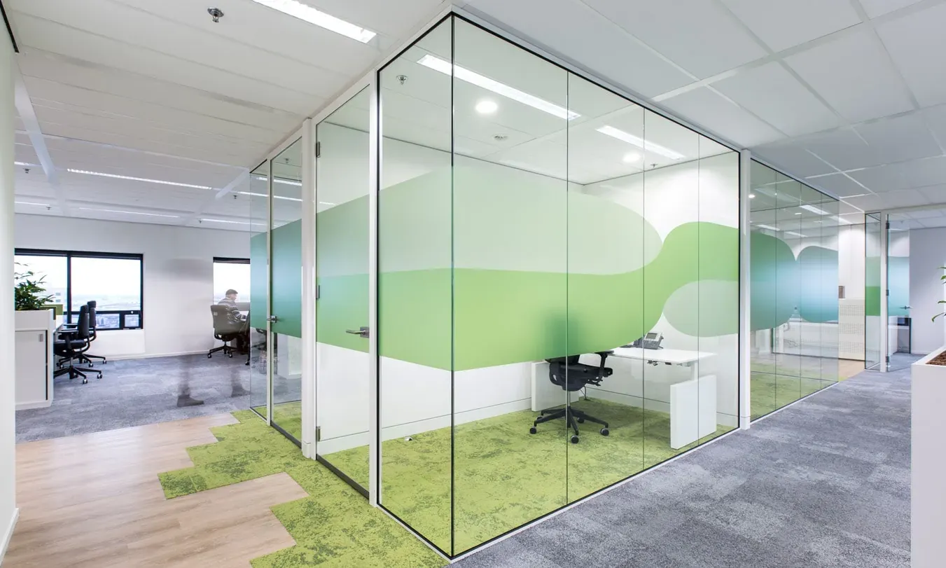 Moderne kantoorruimte met glazen wanden en groene decoratie.