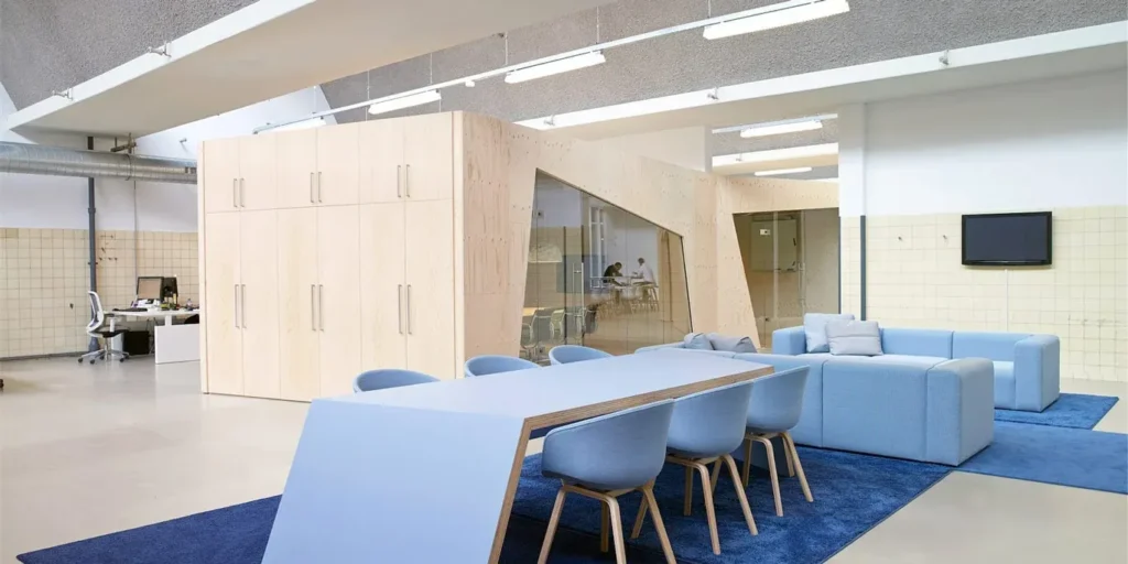 Moderne kantoorruimte met blauwe vergadertafel en zithoek.