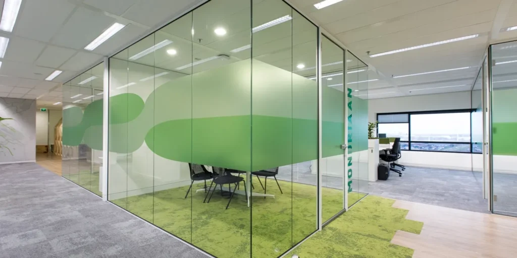 Glazen vergaderruimte in een modern kantoor met groene accenten.