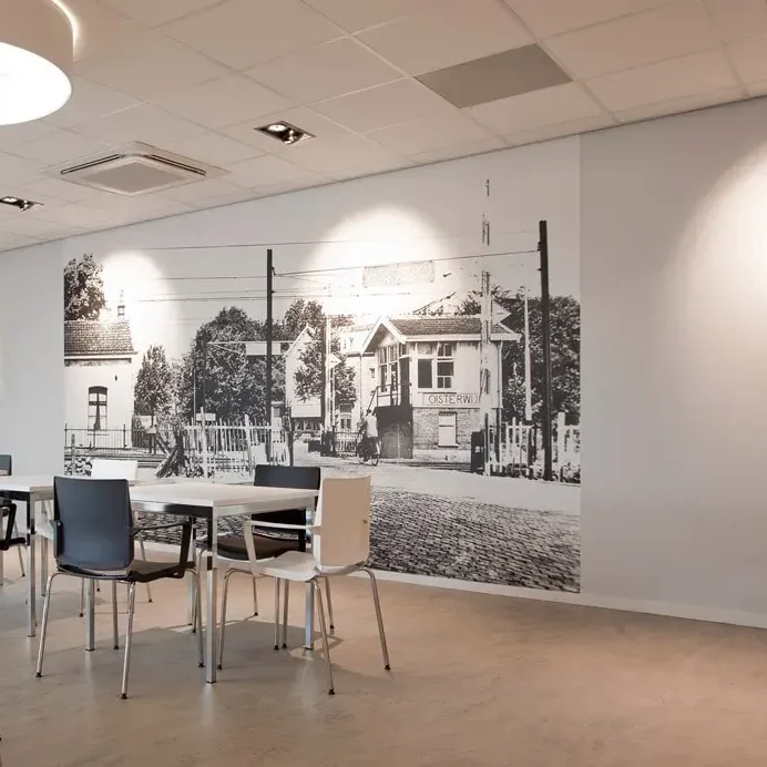 Moderne kantine met tafels, stoelen en foto van Oisterwijk op de muur.