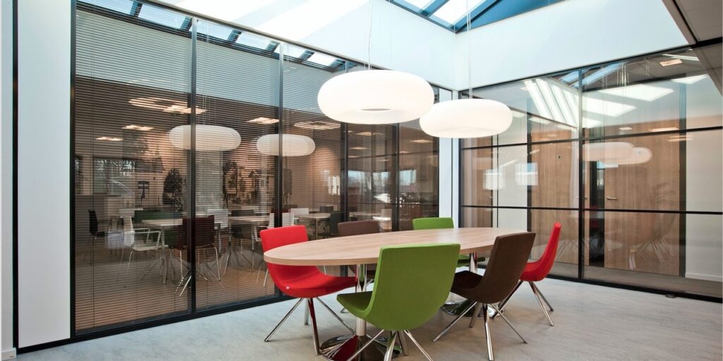 Moderne vergaderruimte met ovale tafel en gekleurde stoelen in een kantoor.