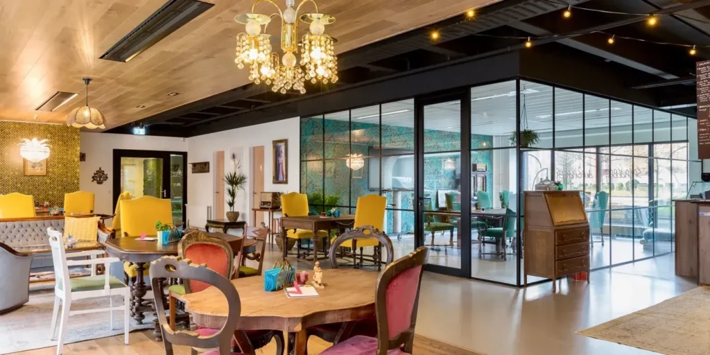 Vintage café interieur met houten tafels, gele stoelen en een kroonluchter.