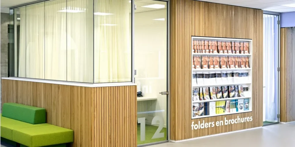 Display met folders en brochures aan een houten wand in een moderne ruimte.