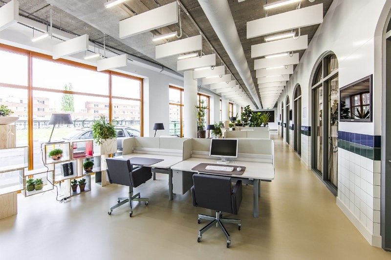 Open kantoorruimte met moderne werkplekken en veel natuurlijk licht.
