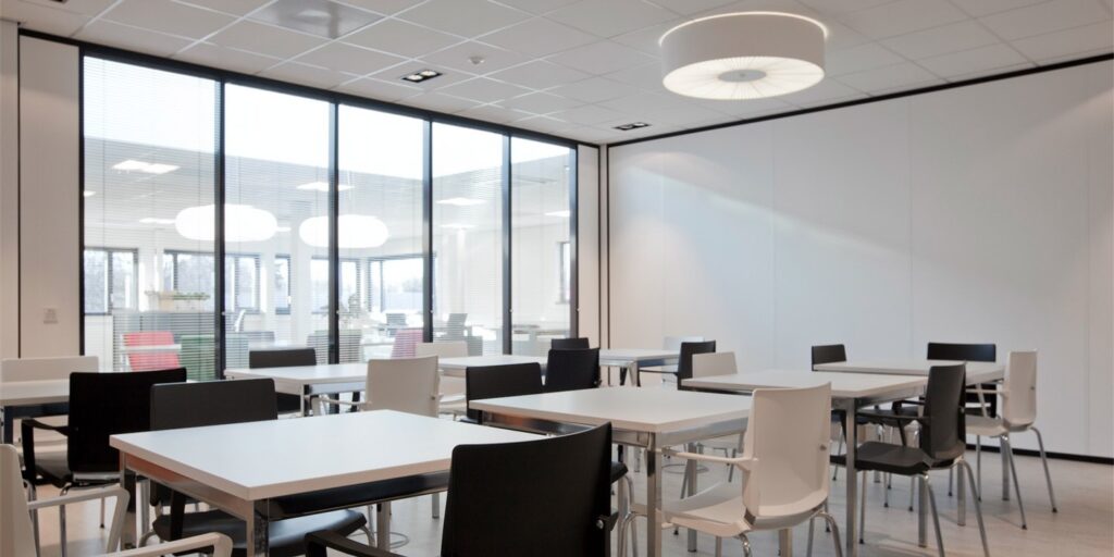 Moderne vergaderruimte met witte tafels en zwarte stoelen in een kantoor.”