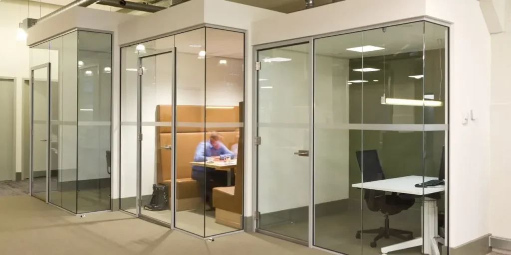 Glazen vergaderruimtes in een kantooromgeving, werknemer aan het werk.