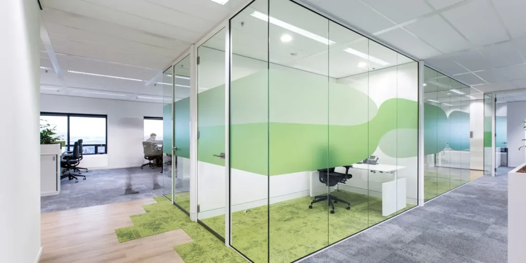 Moderne kantoorruimte met glazen wanden en groene decoratie.