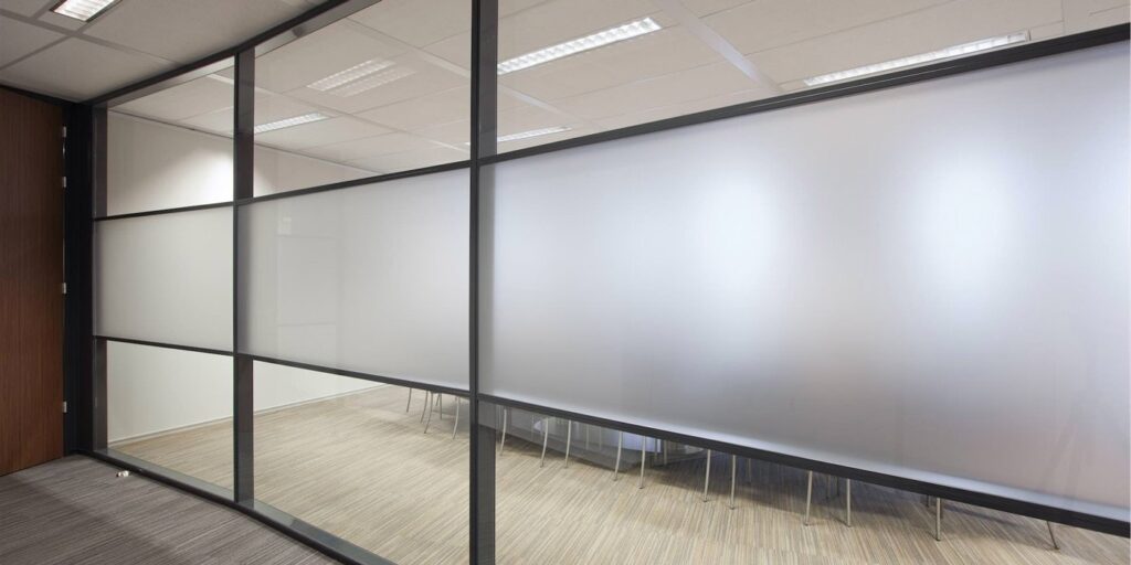 Glazen wand in een kantoorruimte, gedeeltelijk matglas voor privacy.