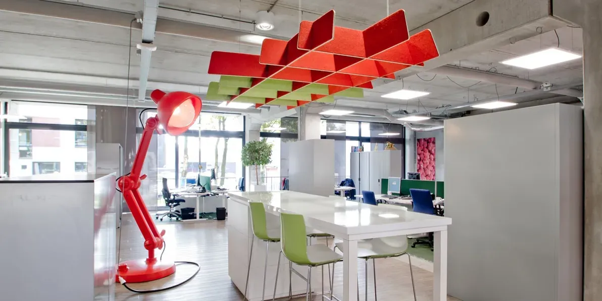 Modern kantoorinterieur met rode lamp en akoestische panelen.