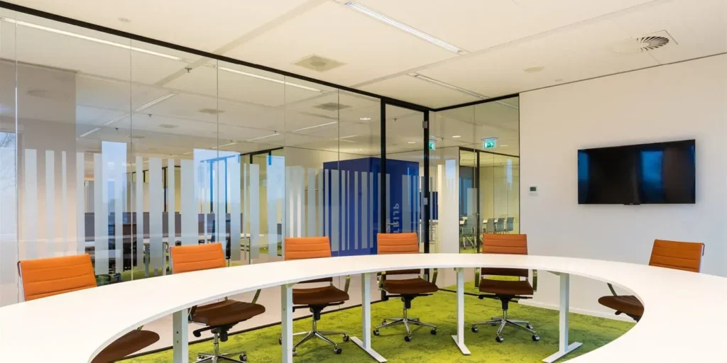 Moderne vergaderruimte met glazen scheidingswand en ovale tafel.