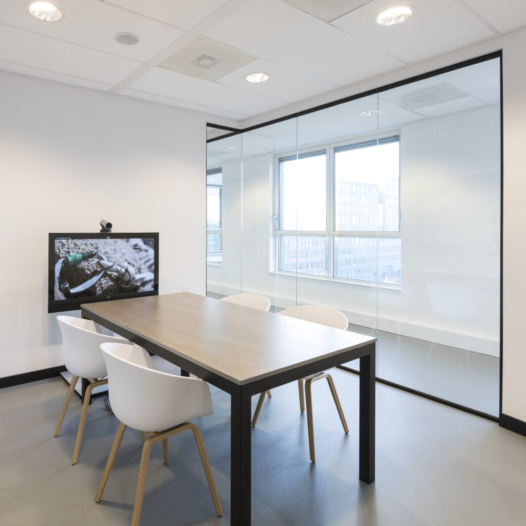 Moderne vergaderruimte met tafel, stoelen en glazen wand.