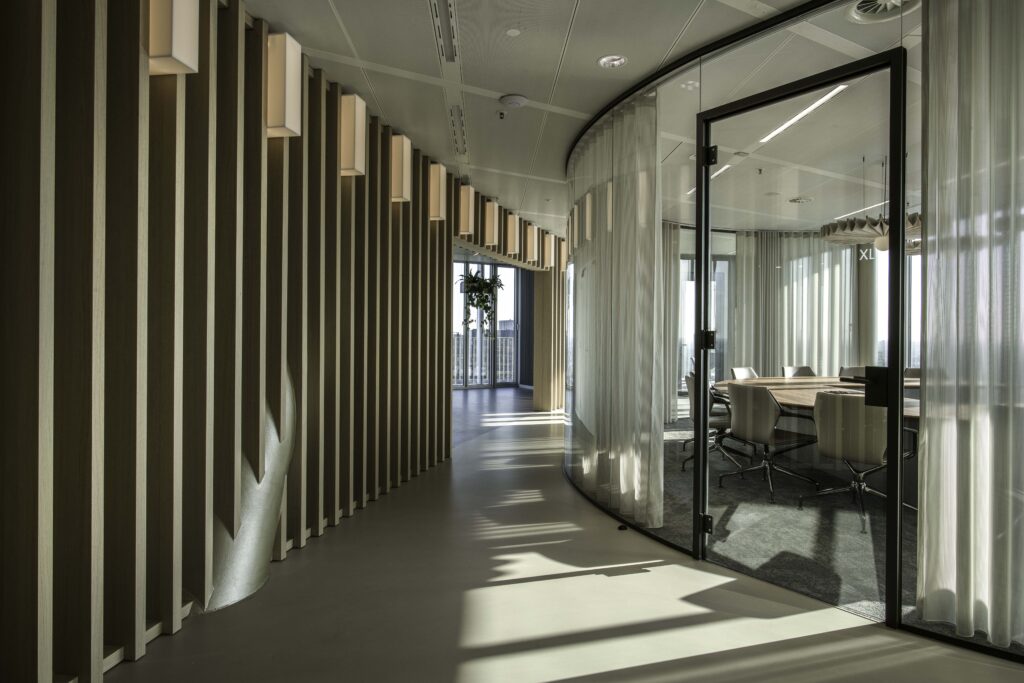 Moderne gebogen glazen wanden in een kantoor met houten lattenwand en vergaderruimte.