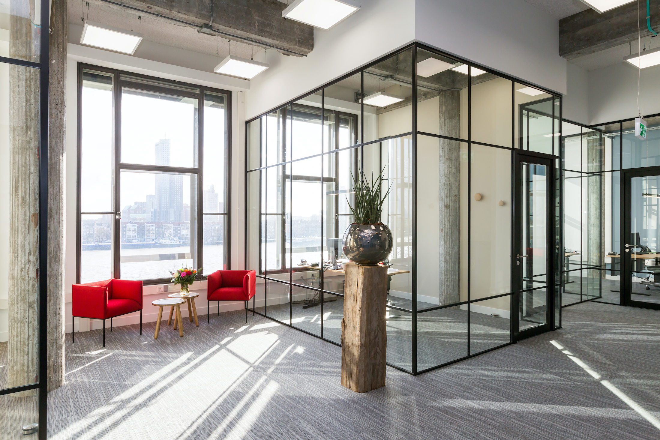 Modern industrieel kantoor in Rotterdam met zwarte glazen wanden en uitzicht op de skyline.